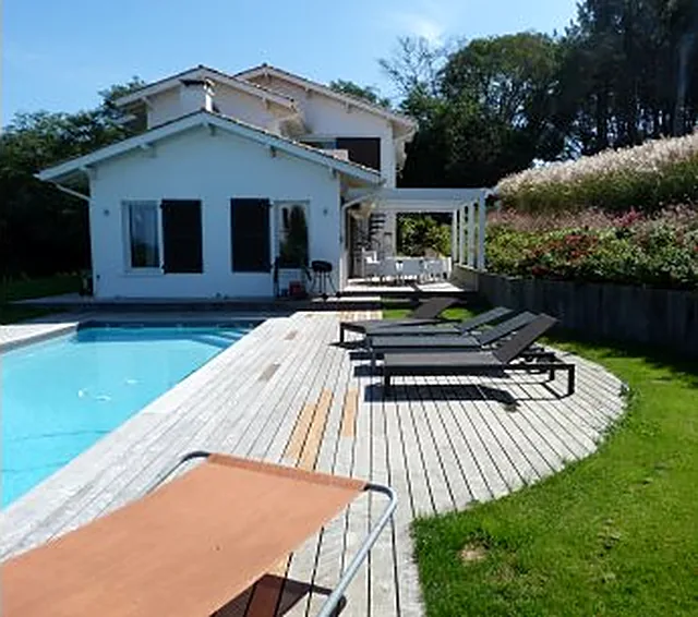 Pool-house en bois et terrasse au bord d'une piscine