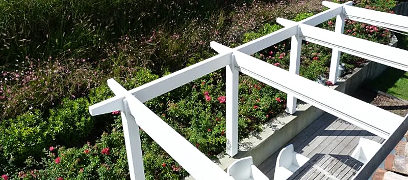 Terrasse en bois avec garde-corps blanc au-dessus d'un jardin fleuri
